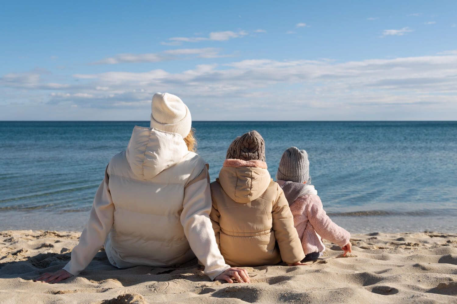 kobieta z dziećmi patrząca na morze, na plaży