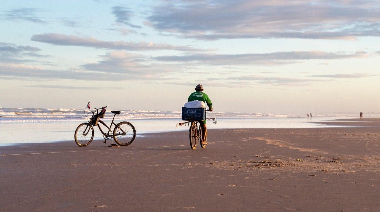 mężczyzna jadący rowerem po plaży