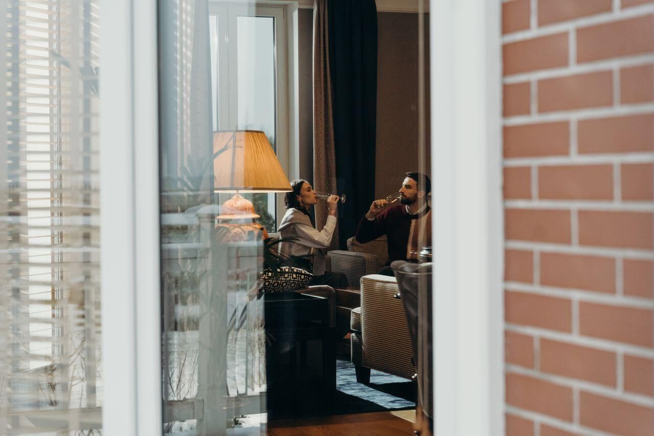 para pijąca szampana w pokoju hotelowym, walizki