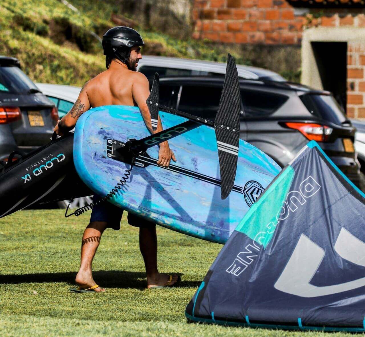 mężczyzna niosący sprzęt do kitesurfingu do samochodu