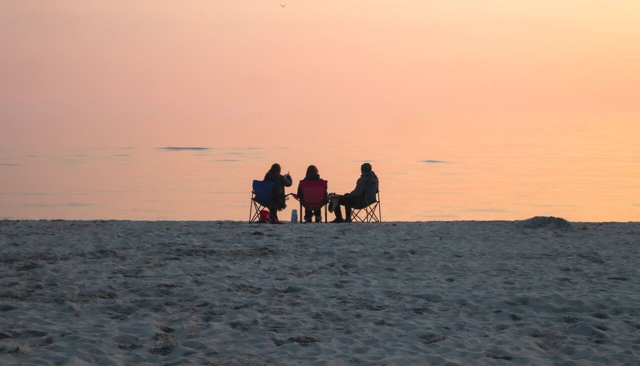 grupa znajomych siedząca na plaży