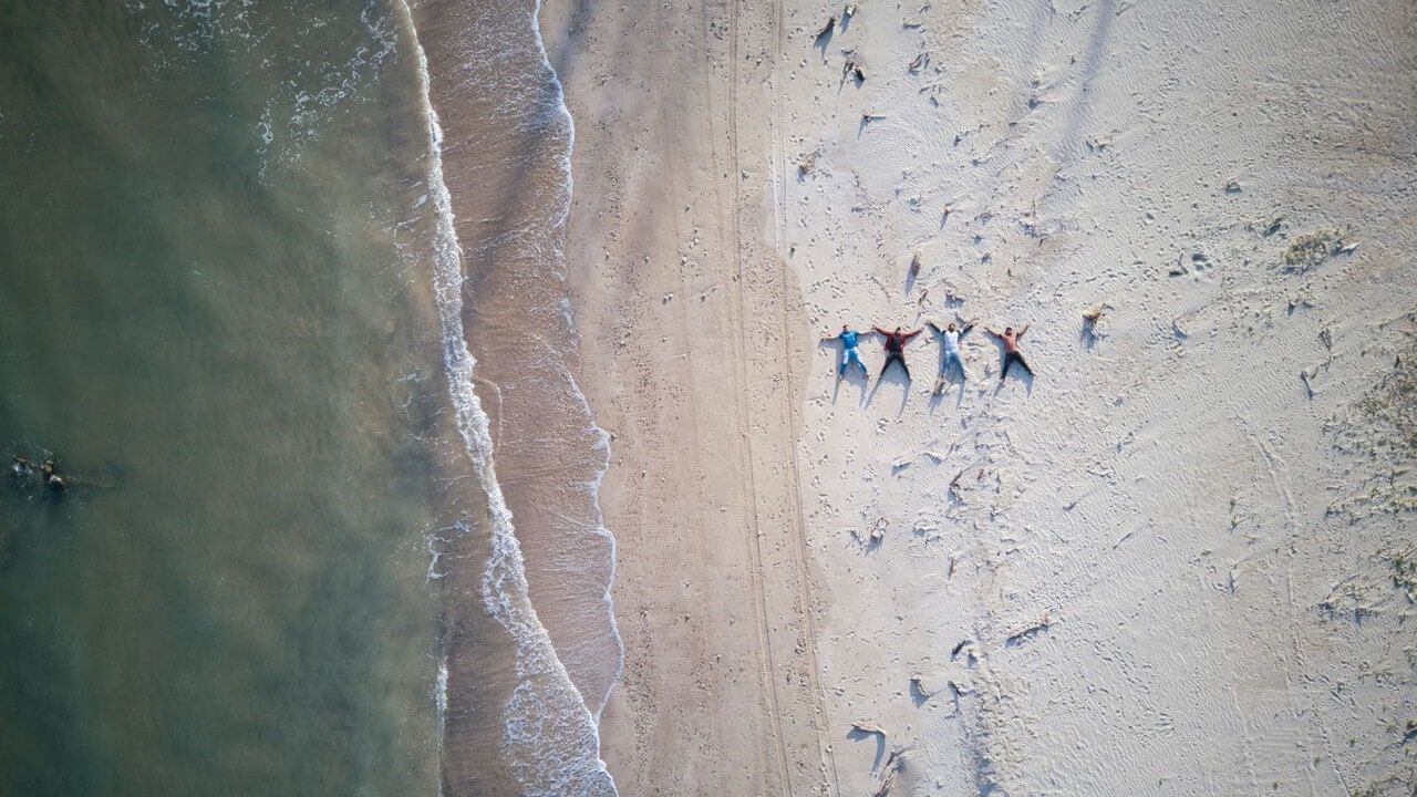 grupa znajomych leżąca na plaży, widok z lotu ptaka