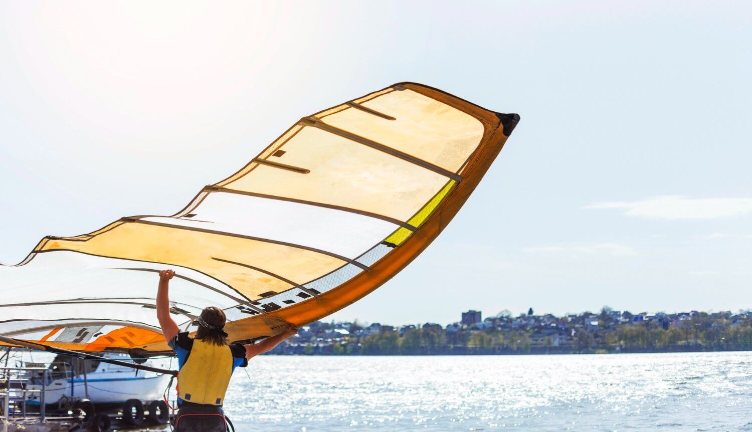 mężczyzna niosący żagiel do windsurfingu