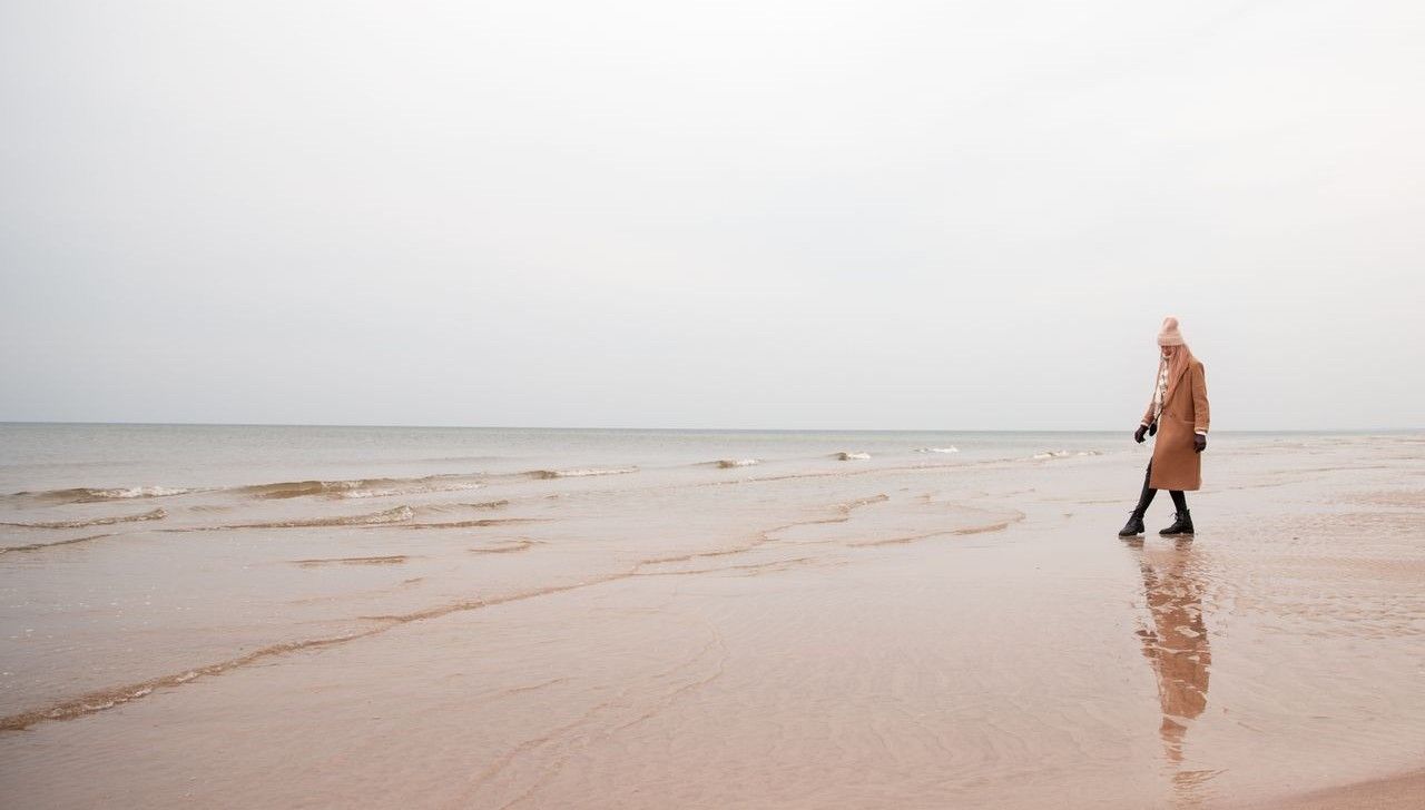 Kobieta spaceruje wzdłuż spokojnej plaży na półwyspie helskim
